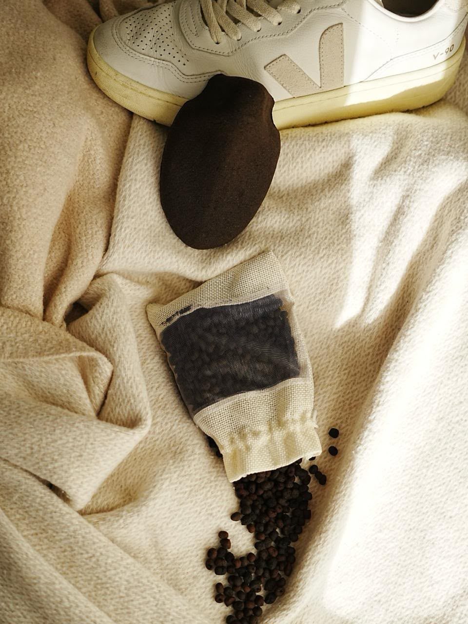 Kahyve shoe tree and a bag of deodorizing pellets next to a white sneaker