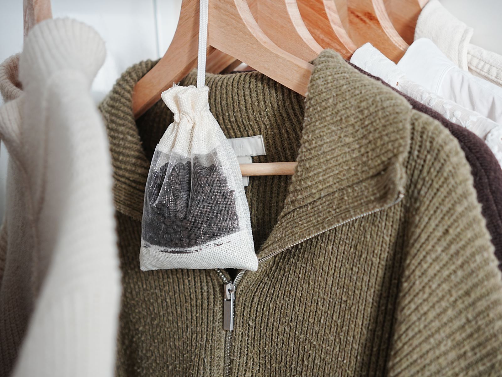 A bag of Kahyve pellets hanging among jumpers in a wardrobe